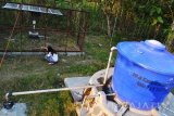 Seorang warga membersihkan ilalang dekat panel mesin pompa tenaga surya di Sendangbumen , Kecamatan Brebek, Kabupaten Nganjuk, Jawa Timur, Sabtu (9/7). Perawatan rutin dilakukan oleh penduduk yang berada di Lereng Gunung Wilis tersebut yang mengandalkan  sumber energi alternatif sumur tenaga surya untuk mendapatkan air bersih guna memenuhi kebutuhan sehari-hari maupun MCK seiring jauhnya akses sumber air khususnya saat musim kemarau seperti sekarang . Antara Jatim/Abdullah Rifai/zk/16.