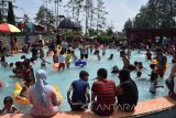 Pengunjung menikmati wisata air panas saat libur Lebaran di Pacet, Mojokerto, Jawa Timur, Sabtu (9/7). Pengunjung wisata air panas Padusan Pacet itu mengeluhkan mahalnya tiket masuk ke lokasi wisata, tidak sebanding dengan fasilitas yang ada, untuk tiket masuk gerbang perlintasan dikenakan Rp 12.500 per orang sedangkan untuk masuk ke kolam air panas harus membayar Rp 10 ribu per orang. Antara Jatim/Syaiful Arif/zk/16