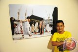 Fotografer Nunung Prasetyo berdiri di sebelah salah satu karyanya yang ditampilkan dalam Pameran Foto Holy Picnic di Gallery Canopy Center, Pontianak, Kalbar, Senin (20/6). Pameran yang digelar hingga 16 Juli tersebut, menampilkan sisi romantisme seorang ayah yaitu Nunung Prasetyo yang bercerita tentang kehadiran anaknya, Saka Kamal Prasetyo dalam perjalanan ziarah ke Makkah dan Madinah. ANTARA FOTO/Jessica Helena Wuysang/16