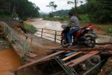 Pengendara sepeda motor melintasi jembatan yang ambruk diterjang banjir bandang di Desa Bendoroto, Trenggalek, Jawa Timur, Senin (11/7). Akses jalan penghubung antar desa di wilayah pesisir selatan Trenggalek itu putus diterjang banjir bandang yang melanda kawasan tersebut pada (Minggu, 10/7). ANTARA FOTO/Destyan Sujarwoko/foc/16.