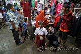 Seorang pembeli mencoba pakaian seragam sekolah kepada anaknya di salah satu stan di Pasar Blauran, Surabaya, Jawa Timur, Rabu (13/7). Menurut para pedagang, penjualan seragam SD, SMP dan SMA menjelang tahun ajaran baru yang akan dimulai pada 18 Juli mendatang tersebut meningkat hingga 300 persen dibandingkan dengan hari biasa. Antara Jatim/Moch Asim/zk/16