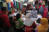 Pedagang melayani pembeli pakaian seragam sekolah di salah satu stan di Pasar Blauran, Surabaya, Jawa Timur, Rabu (13/7). Menurut para pedagang, penjualan seragam SD, SMP dan SMA menjelang tahun ajaran baru yang akan dimulai pada 18 Juli mendatang tersebut meningkat hingga 300 persen dibandingkan dengan hari biasa. Antara Jatim/Moch Asim/zk/16