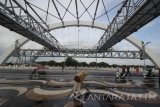 Sejumlah petugas kebersihan membersihkan area Jembatan Suroboyo di Surabaya, Jawa Timur, Senin (18/7). Jembatan dengan panjang sekitar 800 meter dan menghabiskan anggaran Rp200 miliar tersebut merupakan salah satu ikon  baru pariwisata di Surabaya dan termasuk dalam daftar 10 jembatan terbaik di dunia. Antara Jatim/Moch Asim/zk/16