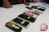 Petugas keamanan menghadirkan barang bukti berupa handphone, uang kertas dan kertas rekap judi  serta sejumlah tersangka  saat  gelar perkara di  Banda Aceh, Kamis (28/7). Sebanyak 18 tersangka dalam kasus judi  (maisir) itu terancam hukuman cambuk pelanggaran Syariat Islam sesuai dengan Qanun no13 tahun 2003. ANTARA Aceh/Ampelsa/16.