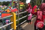 Pengunjung ketika berfoto dengan latar belakang kampung warna-warni di Jodipan, Malang, Provinsi Jawa Timur. Kampung di tepi Sungai Brantas itu kini menjadi kawasan wisata yang ramai dikunjungi wisatawan. (ANTARA FOTO/Ari Bowo Sucipto/Dok). 