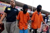 Petugas menggiring kedua pelaku penghasut dan penggeroyokan berinisial MK dan IM yang berhasil diamankan di Mapolresta Medan, Sumatera Utara, Kamis (11/8). Polresta Medan menangkap dua orang pelaku penghasut dan penggeroyokan terhadap empat anggota Polisi saat sedang melakukan penggerebekan narkoba di kawasan Kampung Aur Medan. ANTARA SUMUT/Septianda Perdana/16