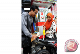 Pedagang Pertamini, Nur Syamawiah (25) mengisi Bahan Bakar Minyak (BBM) eceran ke motor konsumen di Kecamatan Rasau Jaya, Kabupaten Kubu Raya, Kalbar, Senin (15/8). Selain menjual bensin eceran dengan menggunakan Pertamini, Nur Syamawiah juga menjual mesin pengisi BBM eceran Pertamini Elektrik seharga Rp15 juta per unit dan digital seharga Rp25 juta per unit, yang dipasarkan kepada warga yang ingin berjualan BBM eceran. ANTARA FOTO/Jessica Helena Wuysang/16