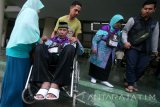 Seorang jamaah calon haji lanjut usia menggunakan kursi roda dibantu keluarganya menuju tempat upacara pemberangkatan di Kota Kediri, Jawa Timur, Selasa (16/8). Kementerian Agama memberi prioritas terhadap calon haji lanjut usia minimal 75 tahun dengan masa tunggu 2 tahun untuk dapat segera naik haji. Antara Jatim/Prasetia Fauzani/zk/16