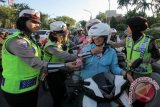 Polisi Wanita (POLWAN) memasang sabuk helm dan memberi kue pengendara motor di Jalan Darmo, Surabaya, Jawa Timur, Selasa (23/8). Kegiatan dengan membagikan helm dan kue kepada sejumlah pengendara motor tersebut dalam rangka menyambut HUT ke-68 Polwan. ANTARA FOTO/Didik Suhartono/wdy/16.