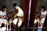 Lurah Putat Jaya Bambang Hartono (kanan) membantu merekam data identitas Srijah (65) penderita polio saat petugas Dinas Kependudukan Catatan Sipil (Dispendukcapil) Surabaya melakukan pembuatan kartu tanda penduduk elektronik (e-KTP) dikediaman Surabaya, Jawa Timur, Selasa (30/8). Dispendukcapil Surabaya jemput bola pada warga yang sakit guna memenuhi target sesuai Peraturan Presiden nomor 112 tahun 2013 tentang perubahan keempat atas Peraturan Presiden nomor 26 tahun 2009 tentang penerapan e-KTP berbasis nomor induk kependudukan secara nasional pada 30 September mendatang. Antara Jatim/M Risyal Hidayat/zk/16