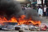 Seorang warga berada diantara ban bekas yang dibakar ketika menolak proses eksekusi lahan di Kawasan Jalan Karya Wisata Medan, Sumatera Utara, Rabu (31/8). Warga menolak rencana eksekusi lahan seluas lima hektar milik PT Pertamina tersebut, karena sudah digunakan warga sejak puluhan tahun sebagai tempat berdagang. ANTARA SUMUT/Septianda Perdana/16