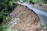 Sejumlah kendaraan melintas di jalan nasional yang longsor di titik Desa Sawahan, Trenggalek, Jawa Timur, Jumat (9/9). Jalur utama menuju Pelabuhan Perikanan Nusantara Prigi dan 10 objek wisata itu longsor sepanjang 50 meter akibat hujan deras yang mengguyur kawasan tersebut pada Jumat dinihari. Antara jatim/Destyan Sujarwoko/zk/16