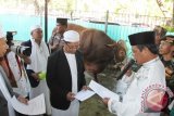 Gubernur Kalsel H Sahbirin Noor menyerahkan hewan kurban Sapi Limosin seberat 875 kilogram dari Presiden Joko Widodo kepada pengurus Masjid Raya Sabilal Muhtadin Banjarmasin, Senin (12/9). Masjid Raya Sabilal Muhtadin menyelenggarakan pemotongan 23 ekor hewan kurban sapi yang dibagikan dalam 2000 kupon. Foto Antaranews Kalsel/Herry Murdy Hermawan 
