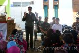 Presiden Joko Widodo (Jokowi) memperlihatkan biskuit dihadapan nelayan di TPI Desa Landangan, Kapongan, Situbondo, Jawa Timur, Rabu (14/9). Dalam kunjungannya Presiden Jokowi membagi-bagikan biskuit kepada anak-anak, ibu hamil, dan ibu yang memiliki balita dalam Program Pemberian Makanan Tambahan (PMT). Antara Jatim/Seno/zk/16. 