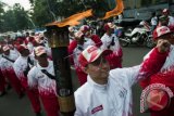 Mantan atlet bulu tangkis nasional Ricky Subagja (kiri) saat memimpin rombongan kirab pembawa obor Api PON XIX Jabar 2016 di Lapangan Gasibu, Bandung. Api tersebut akan digunakan untuk menyalakan kaldron pada upacara pembukaan PON XIX Jabar, Sabtu (17/9/16) malam. (ANTARA FOTO/Novrian Arbi/Dok).