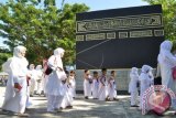 Sejumlah murid PAUD-TK bersama pendamping saat mengelilingi replika Ka'bah saat latihan manasik haji di Asrama Haji Palu, Sulawesi Tengah. Latihan yang diikuti ratusan murid PAUD-TK dari berbagai wilayah di Kota Palu tersebut bertujuan untuk menanamkan pendidikan keagamaan dan pengenalan tata cara ibadah haji kepada anak sedini mungkin. (ANTARA FOTO/Mohamad Hamzah/Dok).