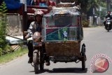 Hendri Pasaribu, mengemudikan becak motif batiknya saat melintas di Garu III Medan, Sumatera Utara, Minggu (2/10). Sejak Tahun 2002, Hendri sudah menggunakan baju batik setiap mengendarai becaknya dan hal tersebut dilakukan sebagai bentuk kecintaannya terhadap batik sebagai warisan budaya Indonesia. ANTARA FOTO/Septianda Perdana/wdy/16