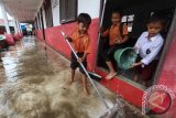 Seorang guru berjalan menembus air yang menggenangi sekolah mereka di Sekolah Yayasan Perguruan Islam Titi Berdikari, Medan, Sumatra Utara, Jumat (14/10). Intensitas hujan yang cenderung tinggi dan buruknya saluran drainase menyebabkan banjir di beberapa wilayah di Medan. ANTARA SUMUT/Septianda Perdana