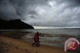 Dua warga berjalan di Pantai Pulau Datok, Kecamatan Sukadana, Kabupaten Kayong Utara, Kalbar, Sabtu (15/10). Badan Meteorologi Klimatologi dan Geofisika (BMKG) menyatakan bahwa dari Sabtu (15/10) hingga Senin (17/10) diperkirakan akan terjadi hujan lebat disertai petir dan angin kencang atau puting beliung di wilayah Kalimantan Barat. ANTARA FOTO/Jessica Helena Wuysang/16