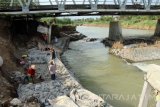 Pekerja memasang bronjong berisi batu di kaki jembatan yang ambrol tergerus banjir di Bandung, Tulungagung, Jawa Timur, Rabu (19/10). Perbaikan tanggul rusak di kaki jembatan penghubung jalan nasional menuju Pelabuhan Perikanan Nusantara Prigi, Trenggalek itu sempat terkendala cuaca buruk yang menyebabkan debit air Sungai Parit Raya meningkat sehingga mengganggu aktivitas proyek. Antara Jatim/Destyan Sujarwoko/zk/16