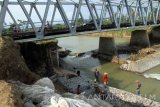 Pekerja memasang bronjong berisi batu di kaki jembatan yang ambrol tergerus banjir di Bandung, Tulungagung, Jawa Timur, Rabu (19/10). Perbaikan tanggul rusak di kaki jembatan penghubung jalan nasional menuju Pelabuhan Perikanan Nusantara Prigi, Trenggalek itu sempat terkendala cuaca buruk yang menyebabkan debit air Sungai Parit Raya meningkat sehingga mengganggu aktivitas proyek. Antara Jatim/Destyan Sujarwoko/zk/16