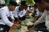 Sejumlah orang makan bersama beralaskan daun pisang ala pesanten saat peringatan Hari Santri 2016 di Magetan, Jawa Timur, Sabtu (22/10). Ribuan santri bersama warga nahdliyin mengikuti istighatsah dan apel dilanjutkan makan bersama beralaskan daun pisang dalam memperingati hari santri 2016. Antara Jatim/Siswowidodo/zk/16