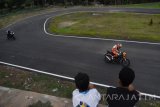 Sejumlah orang melihat pembalap mencoba lintasan sirkuit road race di Bantaran Sungai Madiun, Jawa Timur, Senin (23/10). Pemkot Madiun membangun sirkuit road race guna memberikan fasilitas bagi para pembalap sepeda motor meningkatkan kemampuannya dan meminimalisir adanya pembalap liar di jalan umum. Antara Jatim/Foto/Siswowidodo/zk/16