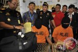 Petugas Bea Cukai menunjukkan barang bukti narkoba yang diselundupkan dua warga Malaysia, Aliff Affan Bin Azhar (kedua kanan) dan Muhammad Shahzadi Bin Shariff (ketiga kiri) di Bandara Ngurah Rai, Denpasar, Bali, Jumat (28/10). Kedua warga Malaysia tersebut ditangkap ketika mendarat di Bandara Ngurah Rai dengan membawa 70,67 gram ganja, 2,89 gram sabu sabu, 15 butir ekstasi dan 150 butir psitropika jenis 