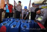 Sejumlah anggota kepolisian memeriksa barang bukti minuman keras (miras) jenis arak di Mapolres Banyuwangi, Jawa Timur, Kamis (3/11). Polisi berhasil menyita sebanyak 3500 liter arak ilegal dengan kandungan alkoholnya mencapai 90 persen yang diangkut menggunakan truk dari Bali, dan rencananya akan diedarkan di Banyuwangi. Antara Jatim/Budi Candra Setya/zk/16.