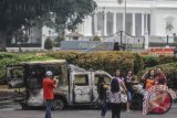 Warga berfoto dengan latar belakang bangkai kendaraan pasca-aksi 4 November di depan Istana Negara di Jakarta, Sabtu (5/11). Usai unjuk rasa yang terjadi pada Jumat (4/11) tersebut kondisi Jakarta kembali kondusif. ANTARA FOTO/Muhammad Adimaja/wdy/16.