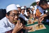 Sejumlah santri memakan ikan makarel secara serentak saat pencatatan rekor Museum Rekor Dunia Indonesia (MURI) di area parkir makam Gus Dur Ponpes Tebuireng Jombang, Jawa Timur, Jumat (18/11). Ponpes Tebuireng berhasil mencatatkan rekor MURI makan ikan makarel secara serentak dengan peserta sebanyak 7.445 santri dan sebanyak 1,6 ton atau setara 8.800 ekor ikan laut yang dimakan. ANTARA FOTO/Syaiful Arif/pd/16