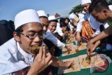 Sejumlah santri memakan ikan makarel secara serentak saat pencatatan rekor Museum Rekor Dunia Indonesia (MURI) di area parkir makam Gus Dur Ponpes Tebuireng Jombang, Jawa Timur. Ponpes Tebuireng berhasil mencatatkan rekor MURI makan ikan makarel secara serentak dengan peserta sebanyak 7.445 santri dan sebanyak 1,6 ton atau setara 8.800 ekor ikan laut yang dimakan. (ANTARA FOTO/Syaiful Arif/Dok).