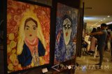 Pengunjung mengamati lukisan yang dipajang saat pameran tunggal pelukis indigo, Edo Adityo di Kota Madiun, Jawa Timur, Minggu (4/12) malam. Pameran tunggal bertajuk 'Indigo dan Bayang-bayang Realitas' tersebut memajang sejumlah ukisan yang mengekspresikan kemampuan Indigo perupa yang memiliki keterbatasan fisik. Antara Jatim/Foto/Siswowidodo/zk/16