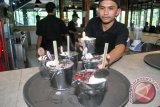 Peracik minuman selesai menyiapkan racikan minuman dari susu sapi di restoran Momo Milk, jalan KH. Abdullah Bin Nuh, Kota Bogor, Jawa Barat, Jum'at (16/12). Restoran yang menyajikan makanan dan minuman serba susu tersebut menggunakan ember mini alumunium sebagai tempat minum layaknya ember susu sapi untuk menarik perhatian pengunjung yang berwisata kuliner ke Kota Bogor. (ANTARA FOTO/Arif Firmansyah/16).