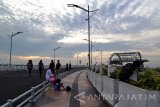 Sejumlah warga menikmati pemandangan sunsite di Jembatan Suroboyo, Sabtu (17/12). Wisata yang diharapkan mampu mendongkrak perekonomian warga pesisir dan juga terintegrasi dengan Sentra Ikan Bulak tersebut, menjadi salah satu tempat favorit saat libur panjang sekolah untuk menikmati panorama sunsite dan air mancur menari. Antara Jatim/Abdullah Rifai/zk/16