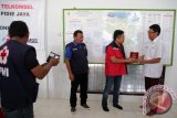 Direktur Utama Telkomsel Ririek Ardiansyah (tiga kiri) menerima plakat terima kasih dari pengurus PMI Pusat J Dwi Hartanto (kanan) seusai menyerahkan bantuan untuk korban gempa dari pelanggan telkomsel di Pidie Jaya, Aceh, Minggu (18/12). Telkomsel menyalurkan bantuan tahap pertama Rp1 miliar itu hasil donasi pelanggan yang dikirim melalui SMS 7788 sejak 8 Desember 2016. (ANTARA Aceh/Irwansyah Putra)