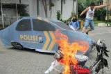 Polisi berperan sebagai pengunjuk rasa merusak replika mobil polisi saat simulasi penanganan unjuk rasa anarkis di Polrestabes Surabaya, Jawa Timur, Selasa (20/12). Kegiatan yang digelar Satreskrim Polrestabes Surabaya tersebut merupakan latihan fungsi peningkatan kemampuan bidang Satreskrim dalam penegakkan hukum terhadap unjuk rasa anarkis. Antara jatim/Didik Suhartono/zk/16