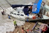Sejumlah masyarakat memasang tali di sebuah perahu layar (yacht) milik wisatawan asal Australia yang terdampar di Kupang, NTT, Kamis (22/12). Yacht tersebut terdampar di Kupang akibat cuaca buruk yang melanda wilayah perairan NTT. ANTARA FOTO/Kornelis Kaha/wdy/16.