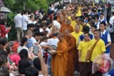 Warga memberikan sedekah kepada Bhikkhu dan Samanera saat tradisi Pindapatta atau menerima dana makanan dari umat sambil berjalan kaki di kawasan Jalan Mahendradatta, Denpasar, Bali, Sabtu (24/12). Pindapatta massal yang diikuti oleh 48 Bhikkhu dan Samanera dari Indonesia dan Srilanka tersebut merupakan rangkaian dari peringatan 40 tahun Sangha Theravada Indonesia. ANTARA FOTO/Fikri Yusuf/wdy/16.