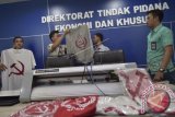 Petugas menyusun sejumlah barang bukti berupa kaus berlambang palu arit saat rilis penangkapan tersangka penjual kaus berlogo palu arit melalu media daring di Bareskrim Polri, Jakarta, Jumat (30/12). Polisi menangkap pelaku karena dianggap menyebarkan paham komunisme dan marxisme serta melanggar UU No.27 tahun 1999 tentang kejahatan terhadap keamanan negara. ANTARA FOTO/Rosa Panggabean/wdy/16.