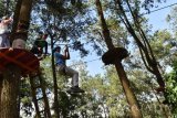 Wisatawan bermain tali rintangan di atas pohon di Mojosemi, Magetan, Jawa Timur, Minggu (1/1). Untuk bisa menikmati permainan uji nyali tersebut, wisatawan membayar biaya Rp80 ribu perorang untuk melintasi 14 rintangan dan Rp50 ribu untuk tujuh rintangan. Antara Jatim/Foto/Siswowidodo/1zk/6