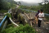 Sejumlah warga memperhatikan jembatan yang ambruk di Desa Cawitali, Kabupaten Tegal, Jawa Tengah, Jumat (6/1). Jembatan sepanjang 25 meter penghubung dua desa tersebut ambruk, sehingga aktivitas warga terganggu karena tidak bisa dilewati. ANTARA FOTO/Oky Lukmansyah/foc/17.