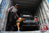 Dua anggota Unit Satwa Detasemen K-9 Dit Sabhara Polda Kalbar menuntun anjing pelacak untuk memeriksa mobil mewah ilegal saat rilis kasus di Mapolda Kalbar, Senin (9/1). Dit Reskrimsus Polda Kalbar menangkap satu mobil kontainer nomor polisi KB 9949 AM bermuatan satu mobil mewah merk BMW ilegal asal Malaysia di kawasan Pelabuhan Dwikora Pontianak. Diduga kuat mobil mewah yang tidak dilengkapi nomor polisi dan dokumen tersebut akan dikirim ke Jakarta. ANTARA FOTO/Jessica Helena Wuysang/16