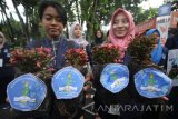 Sejumlah mahasiswa dari Politeknik Kesehatan Kemenkes Surabaya membentangkan poster saat melakukan aksi Gerakan Satu Juta Pohon di Surabaya, Jawa Timur, Minggu (15/1). Aksi yang disertai dengan pembagian bibit tanaman secara gratis kepada warga tersebut dalam rangka Hari Gerakan Satu Juta Pohon yang diperingati setiap tanggal 10 Januari. Antara Jatim/Moch Asim/zk/17