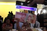 Petugas Bank Indonesia (BI) mensosialisasikan desain uang baru di Kantor Bupati Banyuwangi, Jawa Timur, Kamis (19/1). Kegiatan tersebut, selain mensosialisasikan desain uang baru juga untuk menepis isu hoak yang beredar diantaranya, tentang gambar pahlawan, kesamaan dengan mata uang Yen dan adanya logo palu arit. Antara Jatim/Budi Candra Setya/zk/17. 