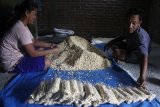 Perajin membuat tempe berbahan baku kedelai impor di sentra industri tempe rumahan di desa Prandon, Ngawi, Jawa Timur, Sabtu (21/1). Perajin tempe di kawasan tersebut mengeluhkan naiknya harga bahan baku kedelai impor sejak sebulan terakhir dari Rp660 ribu menjadi 710 ribu rupiah per kwintal yang membuat biaya produksi membengkak sekitar 20 persen sehingga mereka terpaksa mengurangi ukuran tempe agar tidak merugi. Antara Jatim/Ari Bowo Sucipto/zk/17