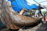 Seorang nelayan membuat perahu di Desa Tanjung Kamal, Mangaran, Situbondo, Jawa Timur, Senin (6/2). Sejumlah nelayan di Desa Tanjung Kamal tidak melaut saat cuaca buruk, seperti angin kencang, gelombang tinggi dan mengisi aktivitasnya dengan membuat perahu, memperbaiki jaring ikan yang rusak dan menjadi buruh tani. Antara Jatim/Seno/zk/17