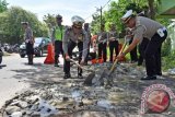 Sejumlah polisi menambal jalan berlubang di Kabupaten Madiun, Jawa Timur. Banyaknya jalan rusak dan berlubang di wilayah tersebut mengakibatkan banyak pengendara mengalami kecelakaan, sehingga polisi berinisiatif menambal jalan berlubang di sejumlah lokasi guna menekan angka kecelakaan lalu lintas. (AntaraFoto)