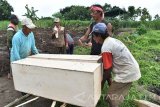 Sejumlah warga memindahkan peti berisi jenazah saat proses pemindahan makam, di lokasi proyek jalan tol Kertosono-Solo di Sawahan, Madiun, Jawa Timur, Rabu (8/2). Sebanyak 155 makam di pemakaman umum tersebut dipindah karena berada di dalam area proyek jalan tol Trans Jawa ruas Solo-Ngawi-Kertosono. Antara Jatim/Siswowidodo/zk/17