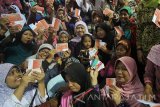 Menteri Sosial Khofifah Indar Parawansa (tengah) bersama keluarga penerima manfaat memperlihatkan buku tabungan Bank BNI di sela-sela acara penyerahan Bantuan Pangan Non Tunai dan Bantuan Sosial Non Tunai di Surabaya, Jawa Timur, Minggu (12/2). Penyaluran perdana Bantuan Pangan Non Tunai (BPNT) tersebut didistribusikan kepada 2.205 keluarga penerima manfaat dari total 24.000 KPM yang ada di Kota Surabaya, yang dapat dicairkan menjadi beras bersubsidi sebanyak 10 kilogram dan gula sebanyak 2 kilogram atau senilai Rp110.000 per penerima bantuan. Antara Jatim/Moch Asim/zk/17